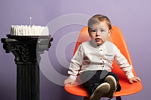 First celebration birthday. Birthday boy sitting on the chair near the cake.