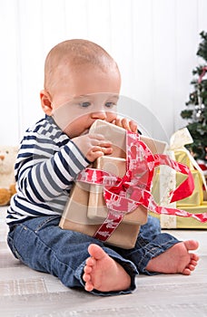 First Christmas: barefoot baby unwrapping a red present - cute l