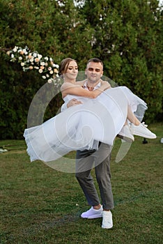 the first dance of the groom and bride in a short wedding dress on a meadow