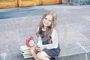 First day of school. Back to school. Child girl schoolgirl elementary school student sits on the steps near the school and holds a