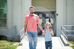 First day at school. Father leads a little child school girl in first grade. School boy going to school with father.