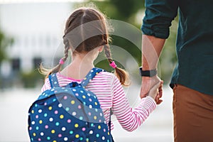 First day at school. father leads little child school girl in f