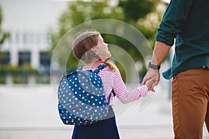First day at school. father leads little child school girl in f