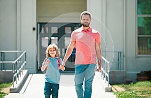 First day at school. Father leads a little child school girl in first grade. School boy going to school with father.