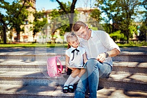 First day at school. Father and little kid daughter sitting on stairs and read book, study lessons. Parenthood and child