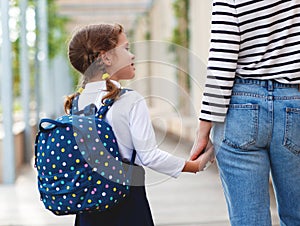 First day at school. mother leads little child school girl in f