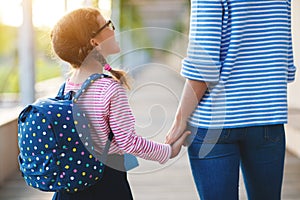 First day at school. mother leads little child school girl in f