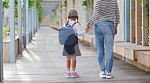 First day at school. mother leads little child school girl in f