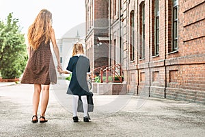 First day at school. Mother leads a little child school girl in first grade.