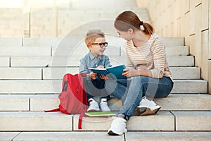 First day at school. mother and little schoolboy son sit on the stairs together