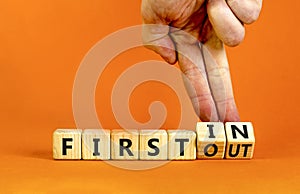 First in first out symbol. Businessman turns wooden cubes and changes words first in to first out. Beautiful orange table, orange