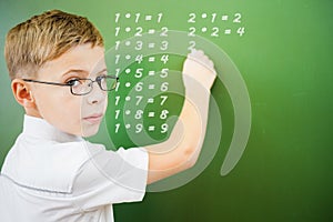 First grade schoolboy wrote multiplication table on blackboard