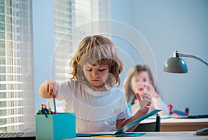 First grader. Back to school. Happy cute child is sitting at a desk indoors. Cild is learning in class.