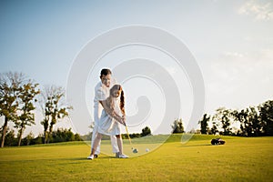 First hit. A man teaches his daughter to play golf and the girl with his help made the first golf club