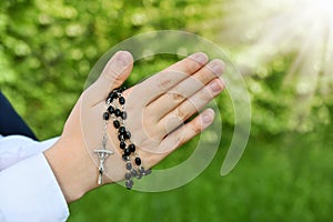 First Holy Communion with rosary around praying boy hands