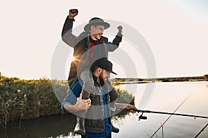 The first joint fishing of adult father and teen son in warm, sunny day.