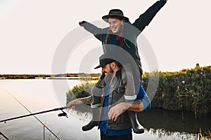 The first joint fishing of adult father and teen son in warm, sunny day.