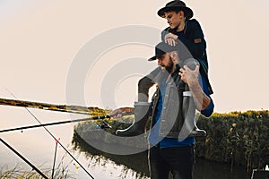 The first joint fishing of adult father and teen son in warm, sunny day.