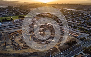 First light of dawn casts a soft glow over a sprawling suburban construction site, with equipment and vehicles