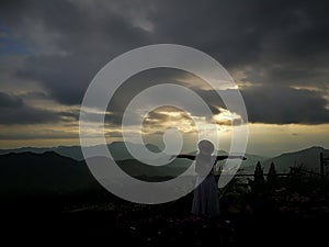 First light of day and the woman breathe fresh air , watching sunshine and mist on top of the mountain.