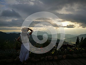 First light of day and the woman breathe fresh air , watching  sunshine and mist on top of the mountain.  Mountain with The fog