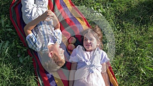 First love, children speaking and having fun on nature lie on a plaid with apples on green grass