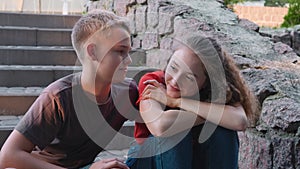 First love and date, a teenage boy hugs a girl sitting on the steps, talking.