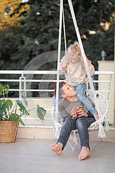 First love, young friends boy and girl swinging on swing together, having fun, laughing.