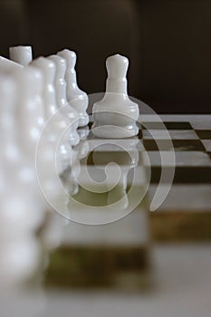 First movement of white chess pawn on marble chessboard as challenge and intelligant fight concept.