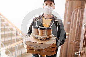 First persom view of delivery man in mask and gloves give pizza and coffe. Stay home photo