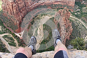 First person perspective shot from a hiker sitting at the edge of a cliff in Zion National Park.