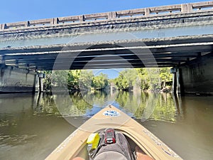 First-person POV of kayak paddling under the Highway 27 bridge on the Sante Fe River, Florida