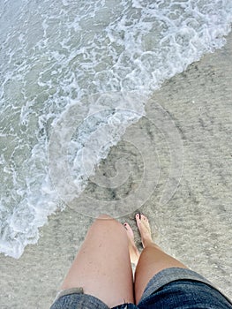 First-person POV of a woman walking through the surf on St. Augustine beach, Florida