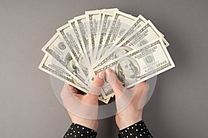 First person top view photo of female hands holding fan of money dollars on  grey background