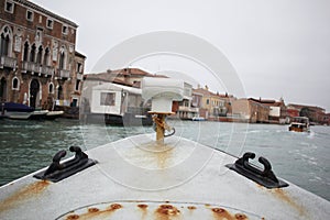 First person view of ancient rusty metal boat with old italian venice city and river scape cloudy Sky