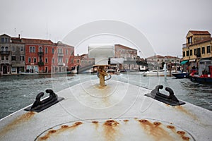 First person view of ancient rusty metal boat with old italian venice city and river scape cloudy Sky