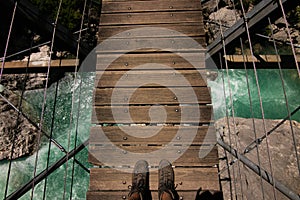 First person view on feet on suspended bridge above water in France