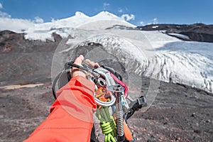 First-person view of a hand with climbing equipment high in the mountains. Mountain climbing