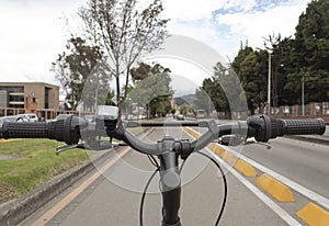 First person view of a handle bars and setam bicycle over a bike path in middle of a city