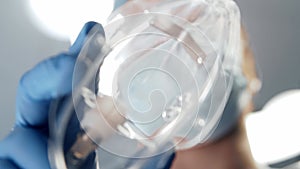 First-person view of the oxygen mask in doctor`s hand. Patient looking to the face of the surgeon in protective mask