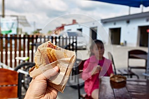 First person view shot of a man and a girl eating hamburger in the street cafe, soft focus, shallow depth of field.