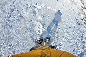 First person view to legs in crampons standing in the snow