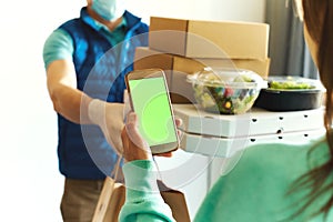 First-person view of woman using smarthone for ordering online, receiving takeout food from delivery man.