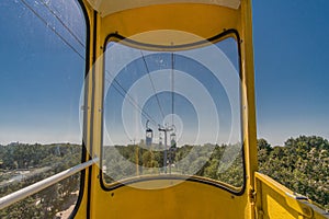 First person view from the yellow cabin of an old cable car on a sunny summer day in the park