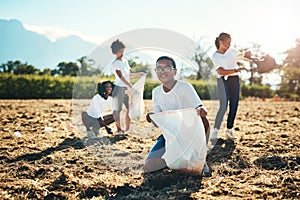 First we play then we pack it away. a group of teenagers picking up litter off a field at summer camp.