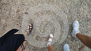 first point view. Top-down view of family legs walking on the road, first-person perspective. Three individuals, mom