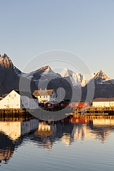First rays of sun on the historic buildings at Hamnøy with snowclad mountains in the background, Lofoten, Norway