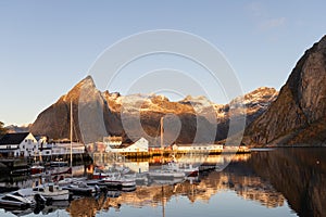 First rays of sun on the rorbuer at Hamnøy with snowclad mountains in the background, Lofoten, Norway