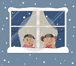 First snow. Children looks at the snow through the window