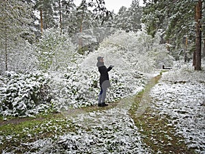 The first snow fell in golden autumn. Happy girl in the woods on the path rejoices